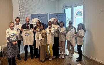 Das Bild zeigt eine Gruppe mit Frauen und M&auml;nnern die ein wei&szlig;es T-Shirt mit der Aufschrift &bdquo;Wir sind H&Auml;PPI&ldquo; tragen