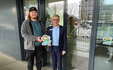 Benedikt Hermle und Norbert Rist stehen vor der T&uuml;r des AOK-KundenCenters in Ravensburg.