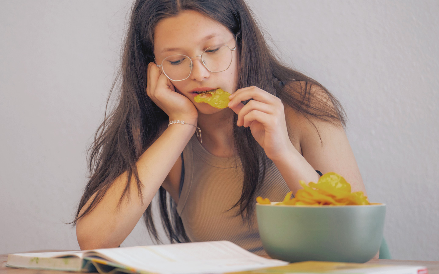 Foto: Frau sitzt am Tisch und isst Chips.