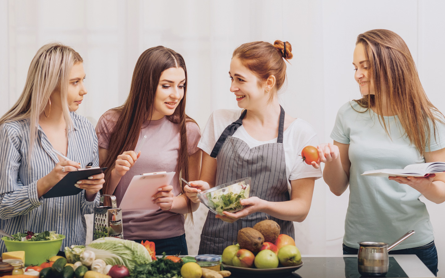 Vier junge Frauen bereiten gemeinsam Früchte und Salate zu. 