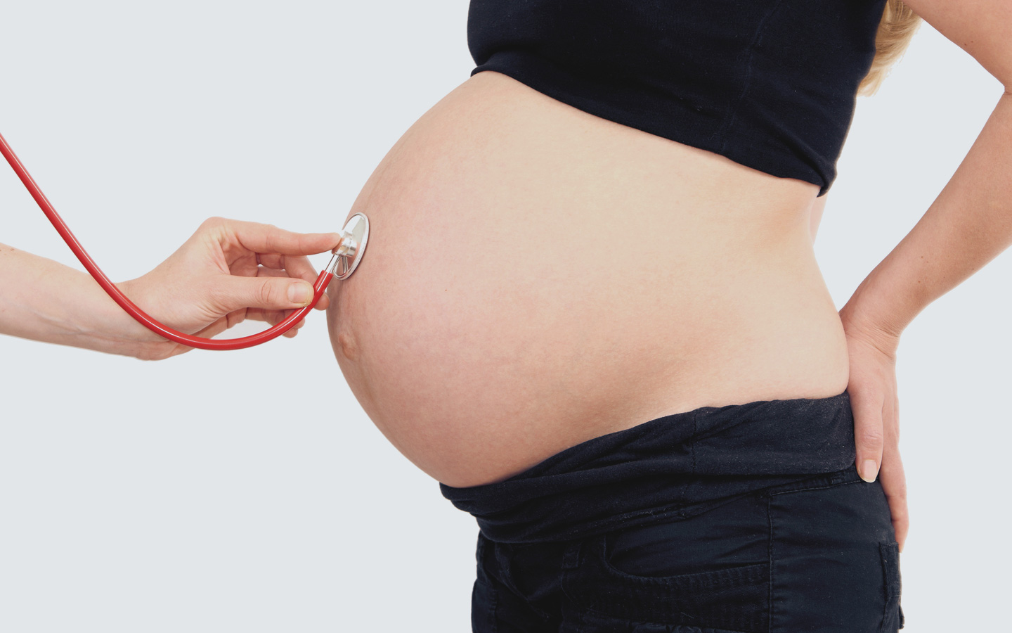 Foto: Bauch von Schwangerer wird mit Stethoskop abgehorcht.