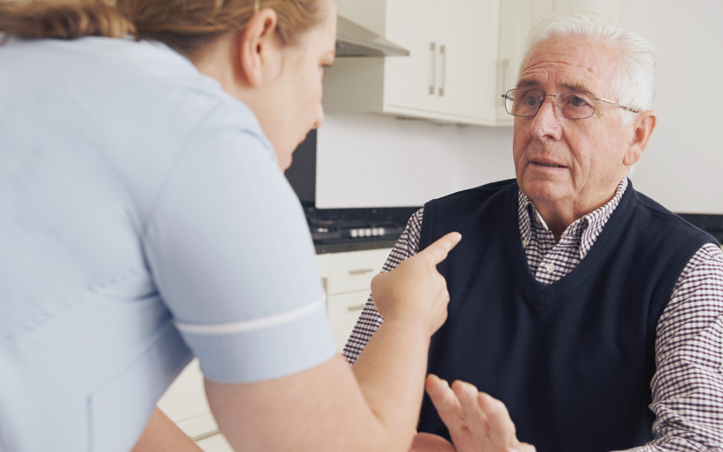 Auf dem Bild erkennt man eine Pflegekraft mit einem auf den Pflegepatienten gerichteten Zeigefinger. Der zu Pflegende wirkt verunsichert.