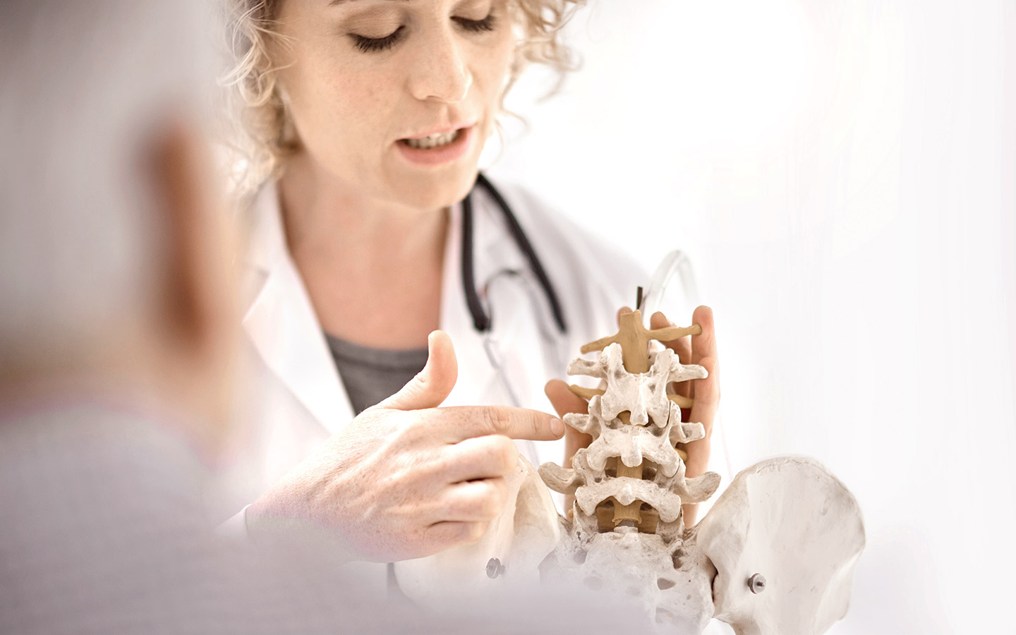 Foto: Ärztin erklärt Knochenstruktur der Wirbelsäule an eine Modell.