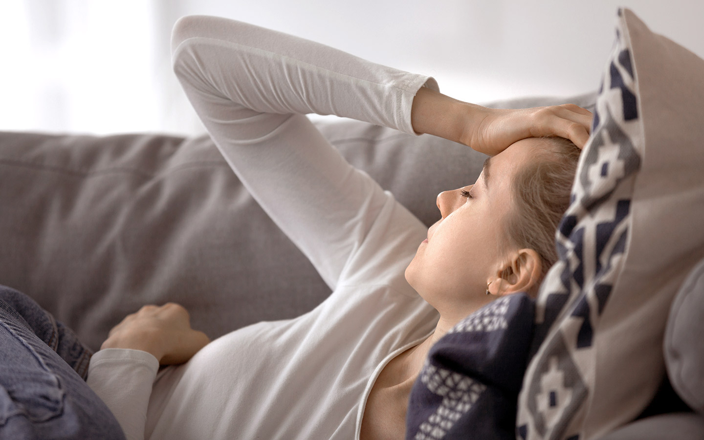 Foto: Frau liegt erschöpft auf dem Sofa.