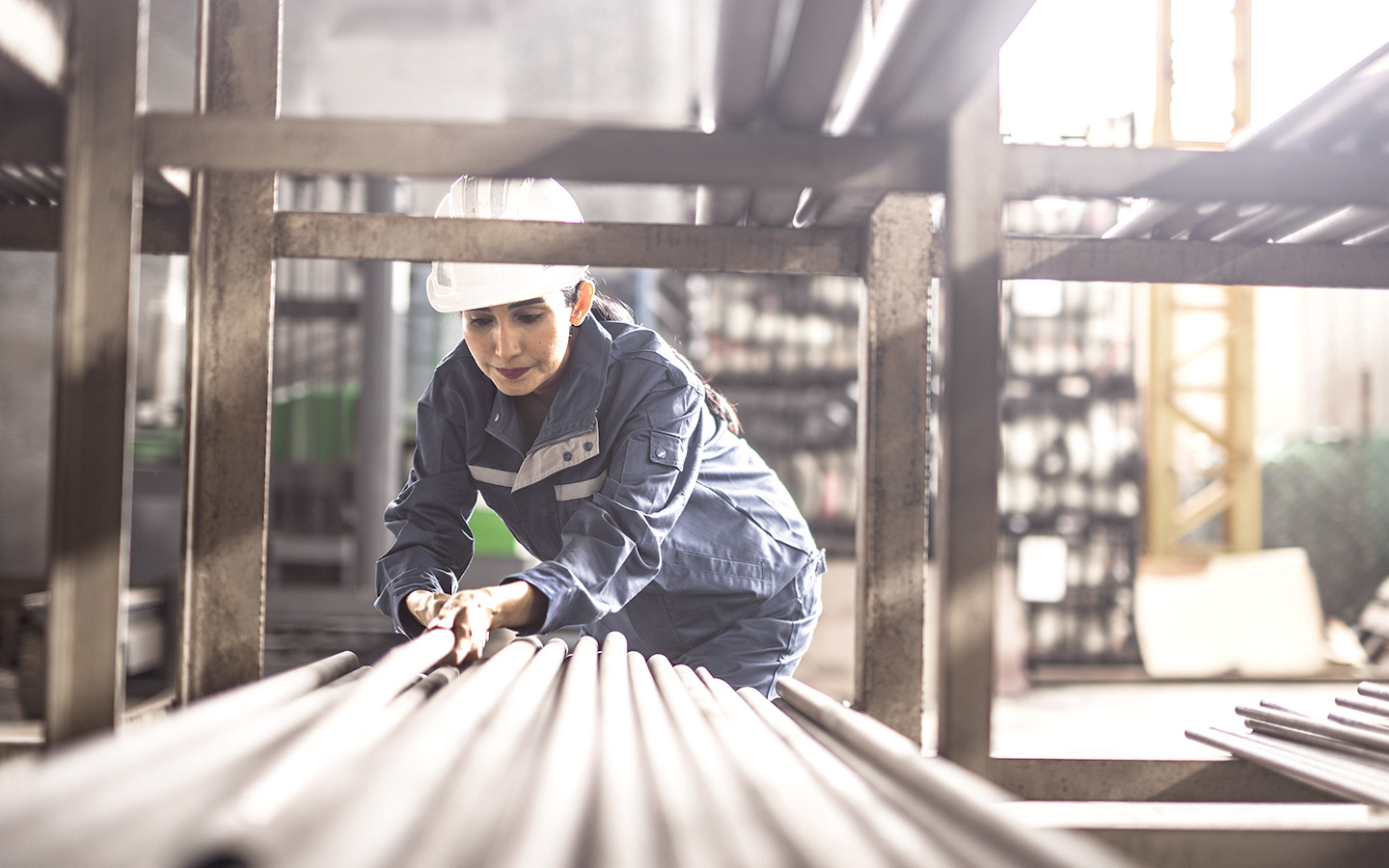 Foto: Frau nimmt Eisenstange in einem Lagerraum in einem Industrieregal.