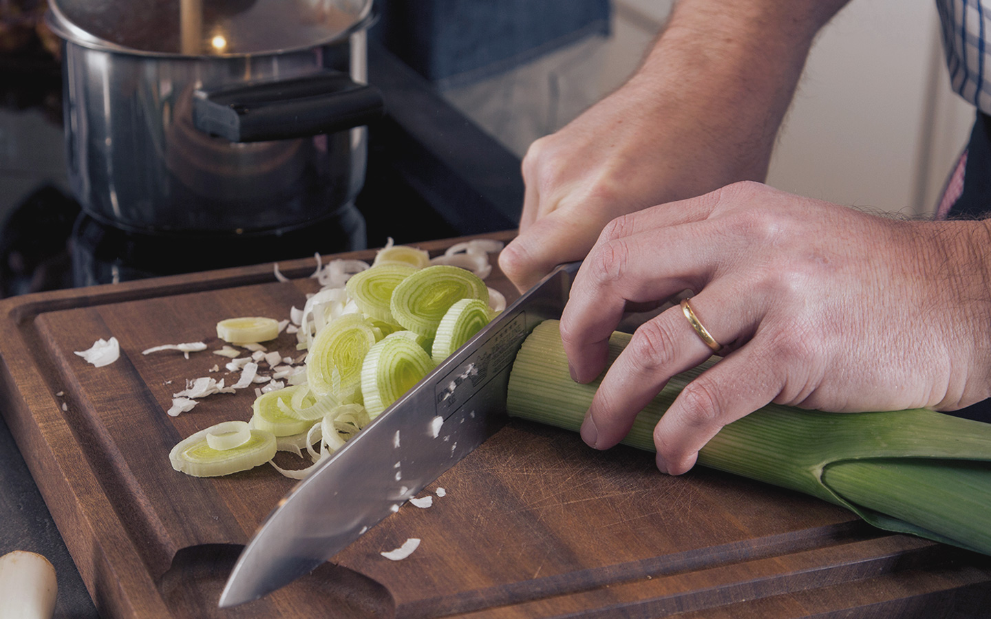 Foto: Ein Mann schneidet eine Stange Porree mit einem Messer.