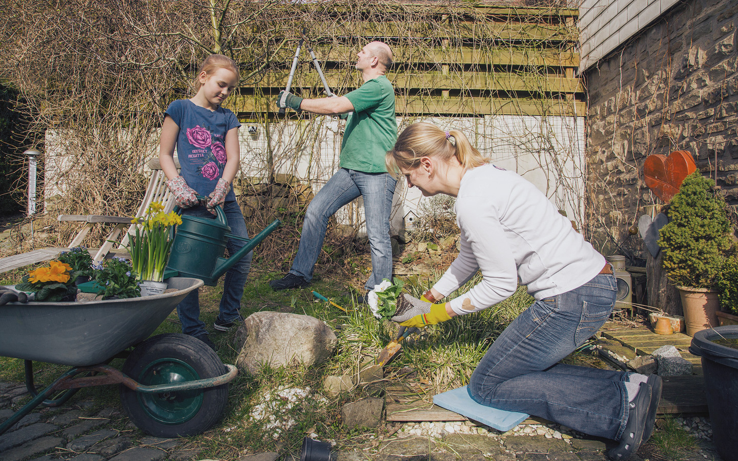 Foto: Eine Frau arbeitet mit zwei Kindern im Garten.
