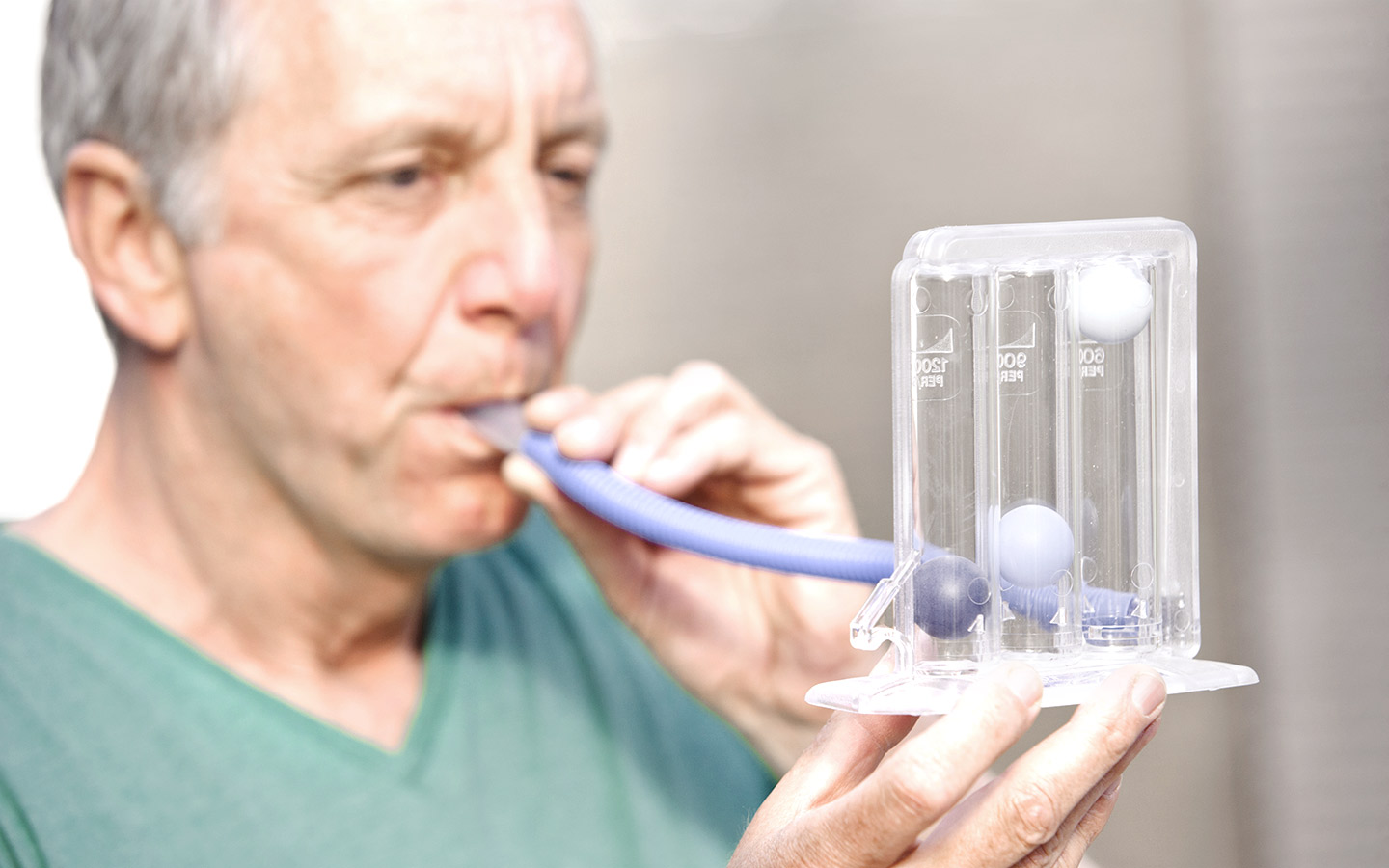 Foto: Mann bläst in ein Lungen-Test-Gerät.