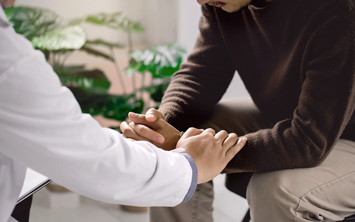 Foto: Ein Arzt hält einen Patienten mitfühlend die Hände.