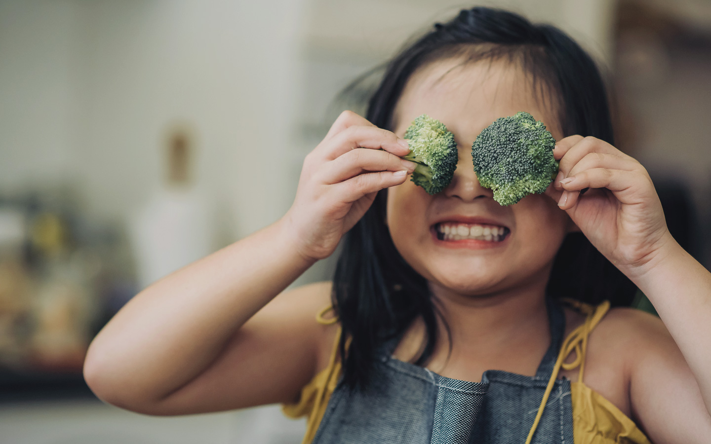Foto: Ein Kind hält sich Brokkoli-Röschen vor die Augen.
