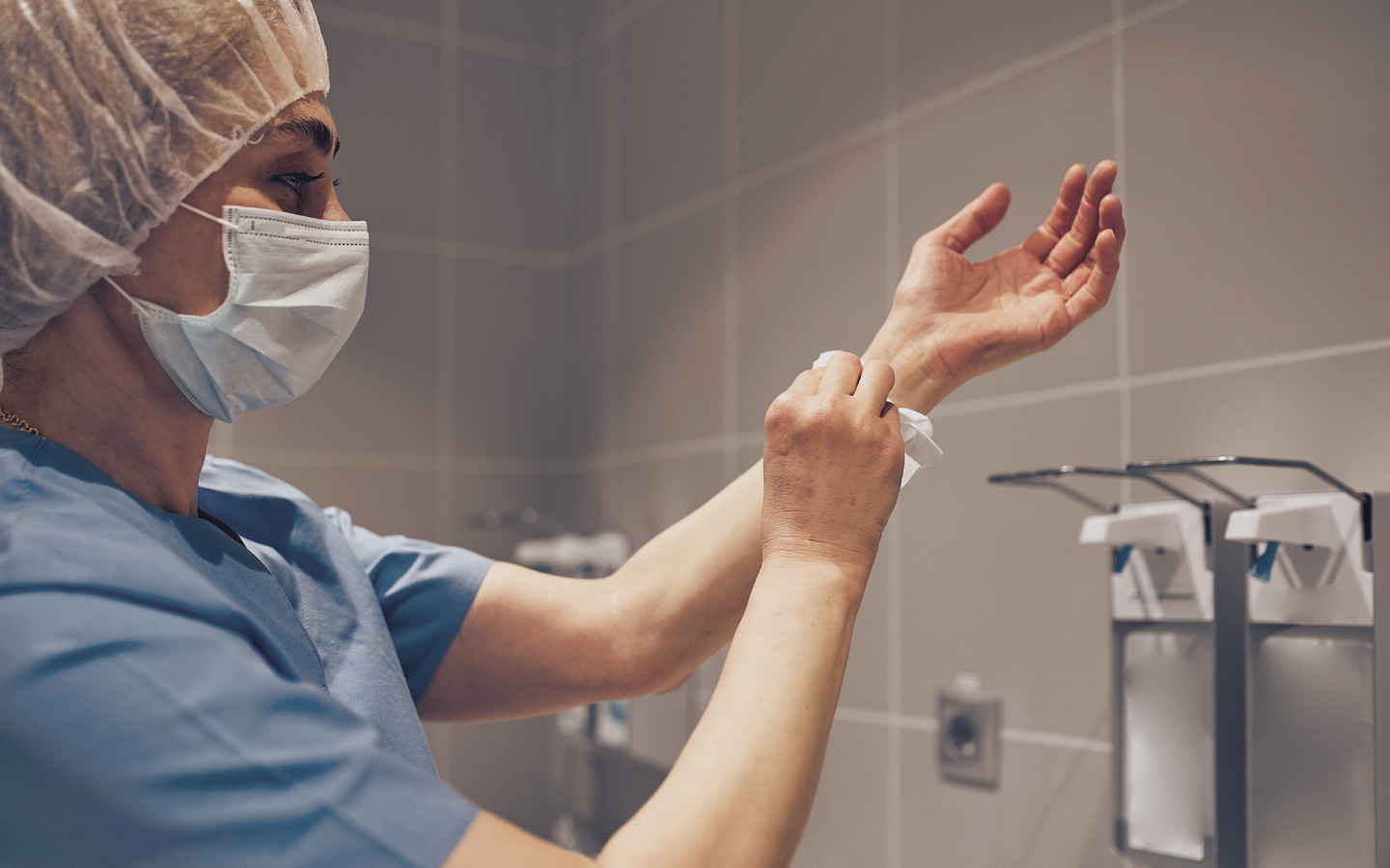 Foto: Krankenhauspersonal trägt Mundschutz, Haarhaube und desinfiziert sich die Hände