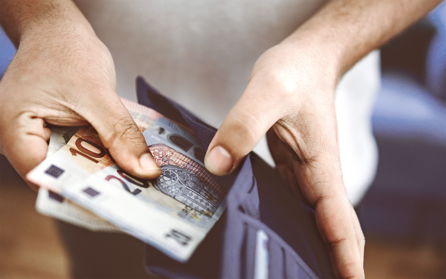 Foto: Eine Person zieht Geldscheine aus einer Geldbörse.