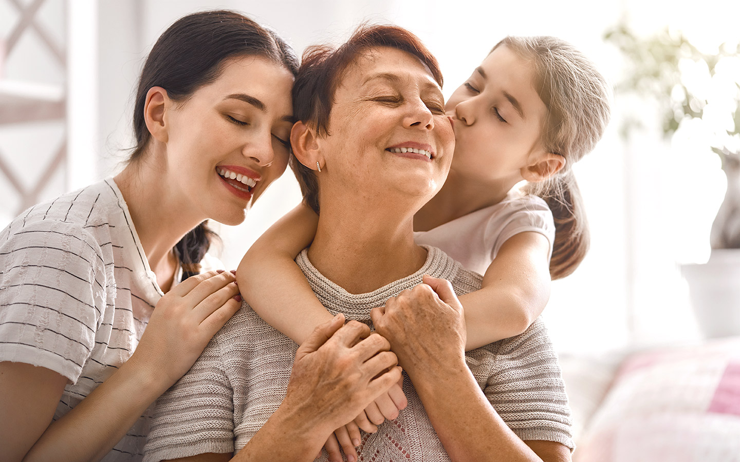 Foto: Drei Generationen Frauen umarmen sich.