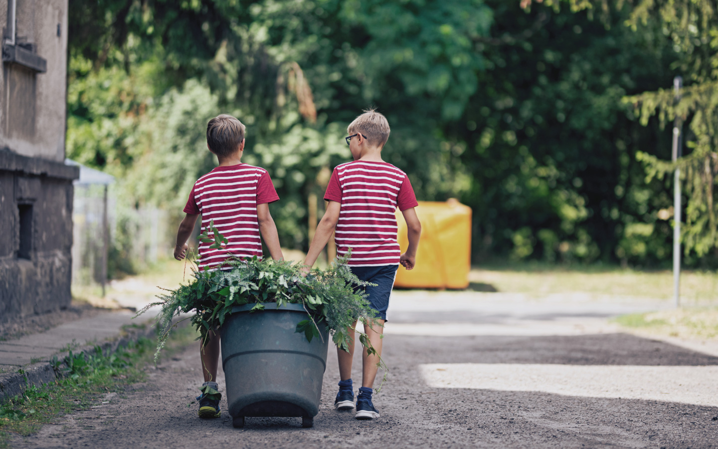 Foto: Zwei Kinder ziehen eine Tonne mit Grünabfällen
