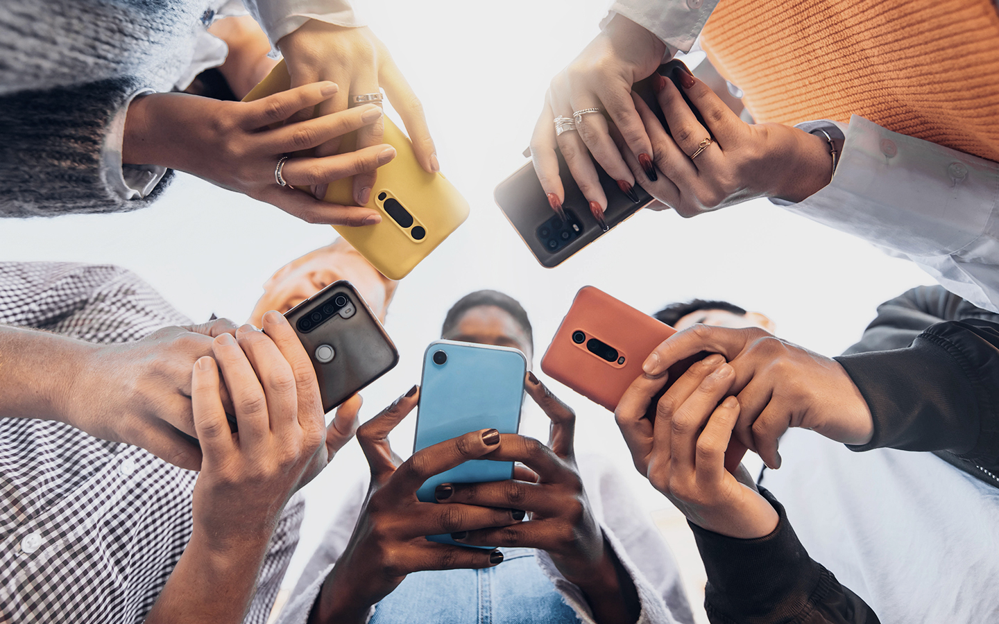 Foto: Jugendliche stehen in einer Runde und haben ein Smartphone in der Hand.
