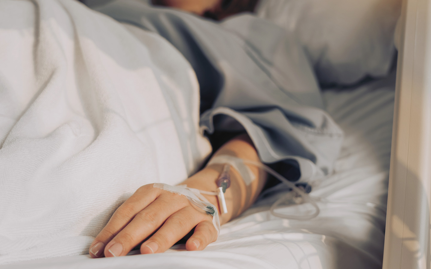 Foto: Hand im Krankenhausbett mit einer Infusion