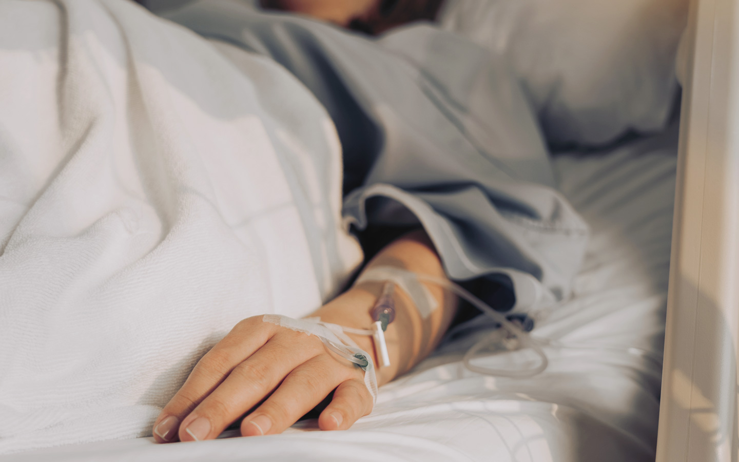 Das Foto zeigt eine Hand auf einem Krankenhausbett.