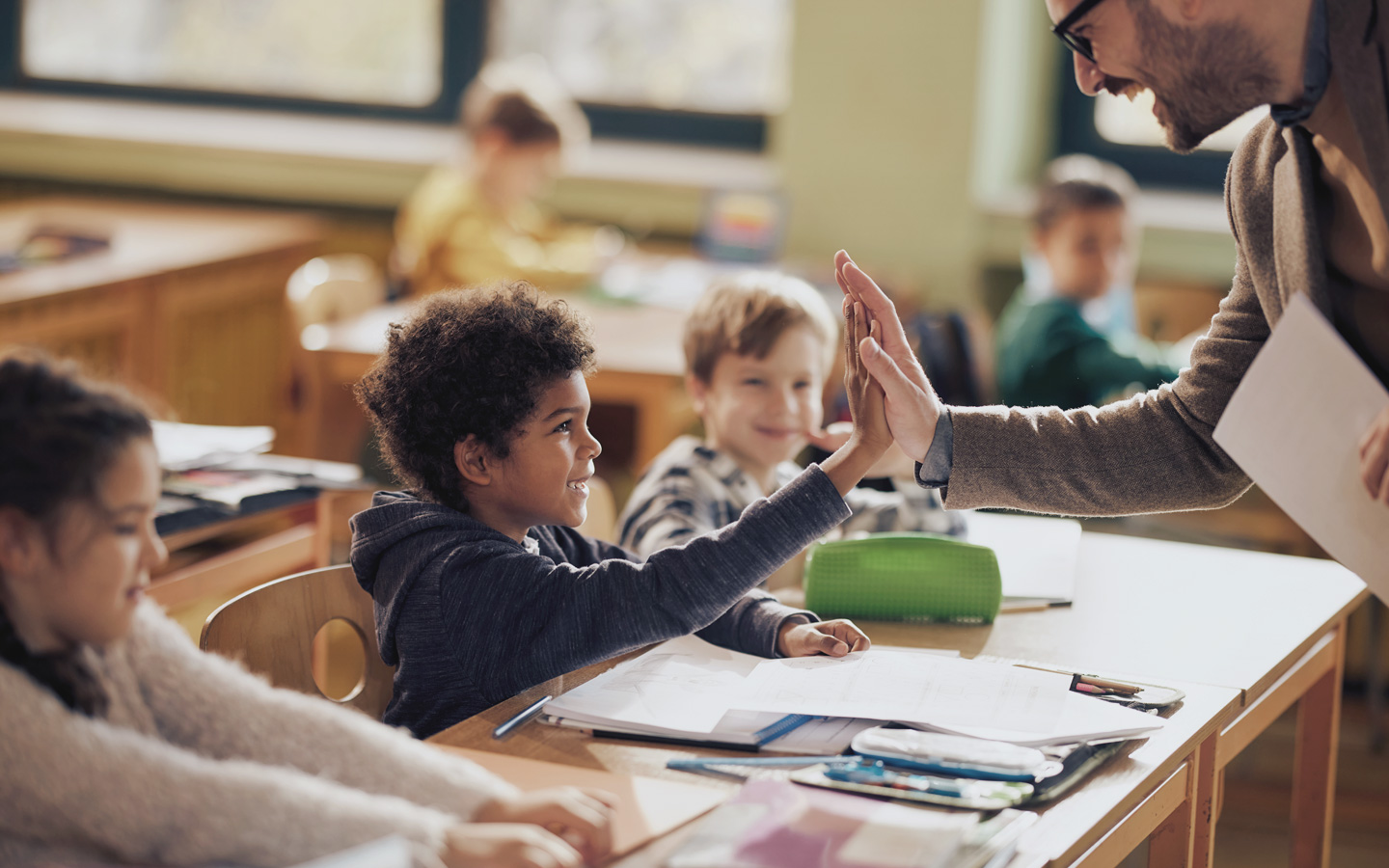 Kinder in der Schule geben dem Lehrer Highfive.